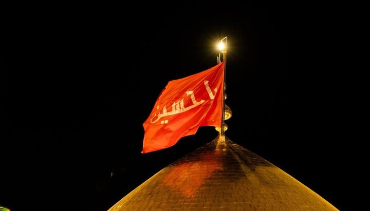 العتبة الحسينية تستبدل الراية السوداء بالحمراء على قبة مرقد الإمام الحسين (ع)