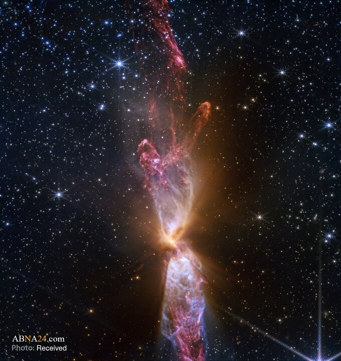 این تصویر جیمز وب سامانه ستاره‌ای Lynds 483 را نشان می‌دهد؛ دو پیش‌ستاره فعال که باعث خروج‌های درخشان گاز و غبار به شکل ساعت شنی شده‌اند. این دو پیش‌ستاره در مرکز ساعت شنی و در دیسکی افقی از گاز و غبار سرد قرار دارند.