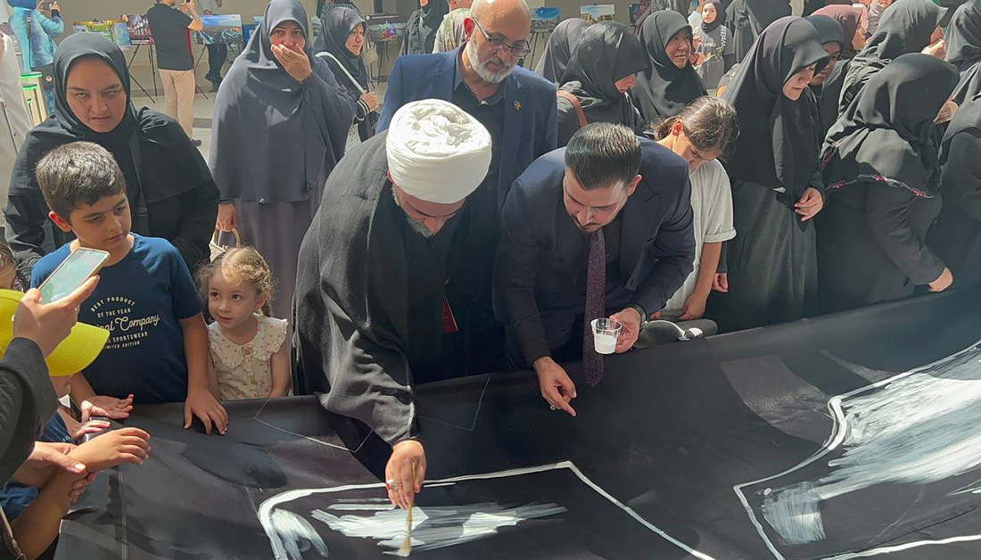 مشاركة محبي أهل البيت (ع) في تركيا بخط كلمة (ياحسين) على راية من مرقد الإمام الحسين (ع)+(صور)